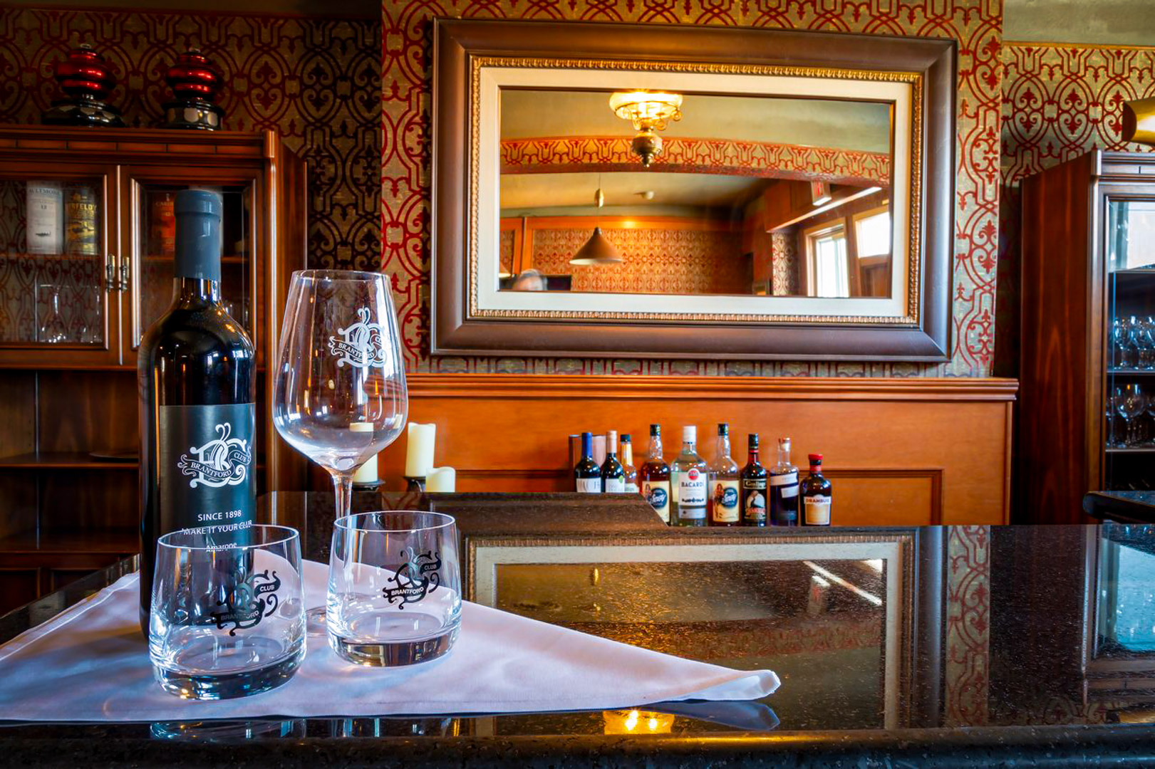 Two glasses and a bottle set on the bar at The Brantford Club